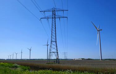 A row of wind turbines combined with high voltage power pylons