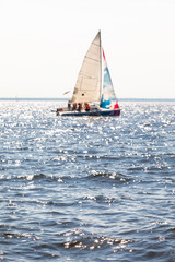 Blurred yacht with raised sails. Defocused sailing boat at full speed on the horizon of the sea on a sunny day