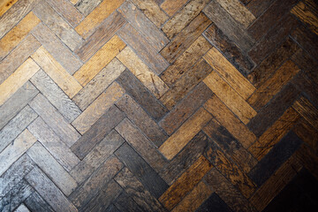 Close up of brown aged old hardwood oak parquet tile floor of herringbone (fish tale) flooring