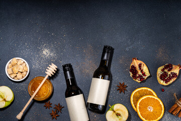 Obraz na płótnie Canvas Different mulled wine ingredients set on black background, flat lay with wine bottle, cinnamon, apple, orange, anise star, simple autumn food drink cooking background