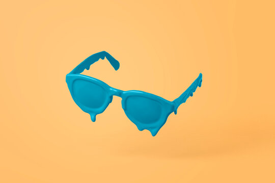 Blue sunglasses are melting from the heat. Creative concept of a sale on an orange background with a coping space.