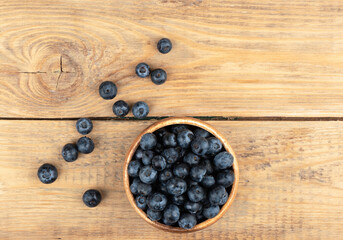 Top view of blueberries or bog whortleberry on a wooden background.
