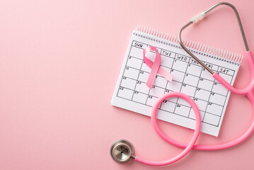 Top view photo of pink ribbon symbol of breast cancer awareness calendar and stethoscope on...