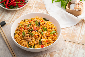 Spicy stir fried instant noodle with minced pork and holy basil leaves in white plate