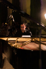 man playing grand piano at a night concert, vertical image