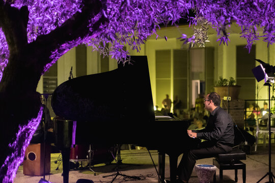pianist playing in the open air at night, purple and yellow lighting