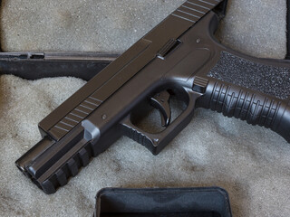 A modern pistol with a plastic frame lying in a box. Close-up