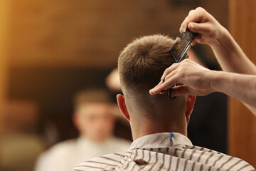 A young male Barber adjusts the hair of a male client. Professional hair care products. Cinematic...