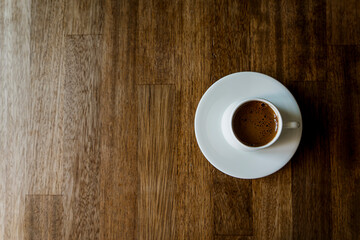 Selective focus on a white cup of  turkish coffee on wooden table background with copy space. Noise effect and grainy texture. Top view.