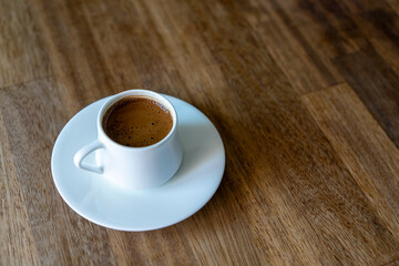 Selective focus on a white cup of  turkish coffee on wooden table background with copy space. Noise effect and grainy texture.