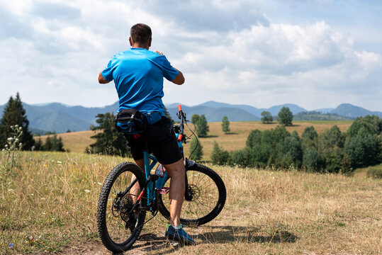 A cyclist, on a full-suspension bicycle, takes pictures of the landscape.