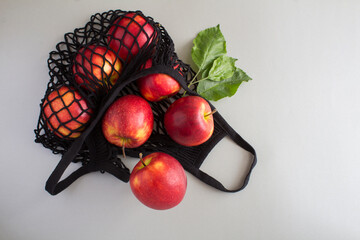 Mesh shopping bag with red apples on the gray background. No plastic bag concept. Top view. Copy space.