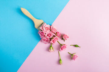Paintbrush with pink roses on the colored background. Top view. Copy space.