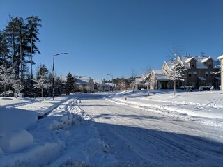 Snowy and icy residential road in a suburban neighborhood with townhouses