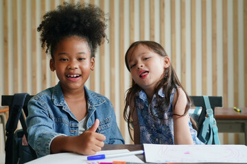 African kids drawing and do homework in classroom, young girl happy funny study and play painting on paper at elementary school. Kid drawing and painting at school