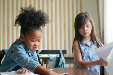 African kids drawing and do homework in classroom, young girl happy funny study and play painting on paper at elementary school. Kid drawing and painting at school