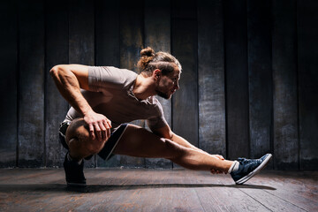 Active athlete do exercises on the floor, intense training on black background. Strong sportsman in...