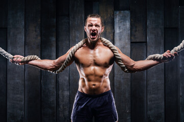 Fototapeta na wymiar Dynamic motion of sportive muscular man, athlete do exercise fitness with battle ropes. Male training upper body working out at hard cross-fit training. Brutal strong bodybuilder pumping up muscles.