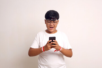 Happy asian boy standing while holding cell phone. Indonesian independence day concept