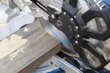 Miter circular saw photographed in the process of work. Tool for carpentry. A man works with a tool. The worker saws the boards. Sawmill. Miter saw for cutting wood at work.