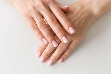 Female hands with beautiful nails with stylish trendy nude manicure.
