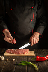 Experienced chef cuts beef raw meat on a cutting board before barbecue. Preparing a delicious meal in the kitchen