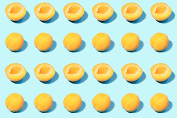 Summer pattern of ripe apricots on a blue background - fruit harvest concept - whole apricots and halves