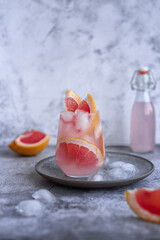 Refreshing homemade summer drink: grapefruit lemonade with ice on a gray concrete background
