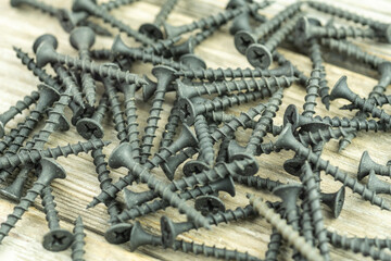 Close-up of scattered large long black screws. A poster for a building materials store or catalog. Building a house.