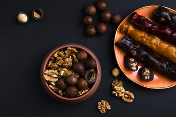 Georgian churchkhela in a plate on a dark table with nuts and other sweets. Close-up