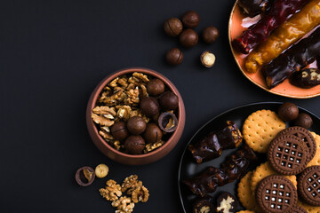 Fototapeta na wymiar Georgian churchkhela in a plate on a dark table with nuts and other sweets. Close-up