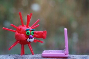 A virus figurine with a laptop. Business, finance and information technology.