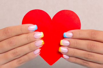 Obraz premium Beautiful female hands with colourful manicure nails with rainbow design