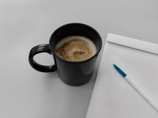Coffee cup with pen and notepad.