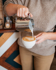 Person pouring a cappuccino a coffee shop