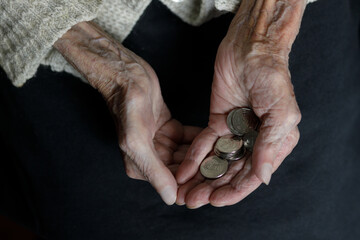 Obraz premium A woman's hands hold several Ukrainian hryvnia coins. Pension, poverty, social problems and the topic of old age. Preservation.
