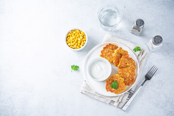 Corn fritters in a plate with sour cream sauce