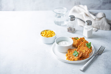 Corn fritters in a plate with sour cream sauce
