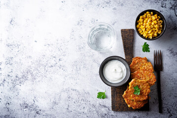Corn fritters in a plate with sour cream sauce