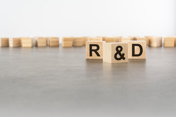 three wooden blocks with letters R and D with focus to the single cube in the foreground in a conceptual image on grey background