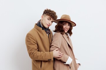 a man and a woman posing on a white background in an autumn coat put their hands in their pockets and sweaters, gently looking forward