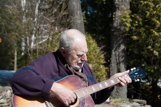 senior man playing acoustic guitar in the garden