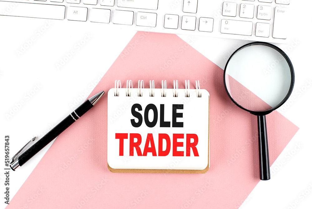 Poster business concept. notebook with text sole trader on pink paper with magnifier, keyboard and pen in t