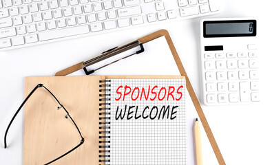 Notebook with the word SPONSORS WELCOME with keyboard and calculator on the white background