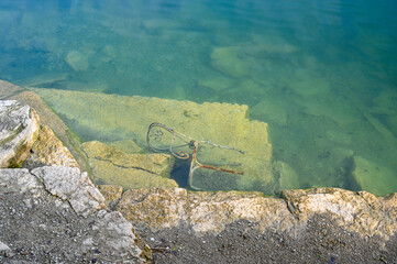 rusty metal chair lying in old quarry filled with water