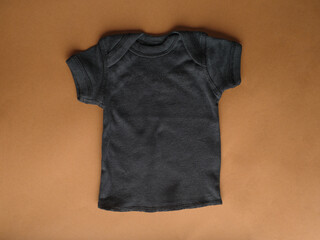 Mockup of a children's black t-shirt for boys made of natural fabric on a beige background. Comfortable sportswear for children. Flat layout for design of prints and logos.