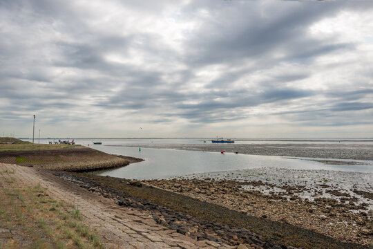 Picturesque view over the entrance to the old harbor from the Oosterschelde estuary at low tide. The photo was taken on a cloudy day near the Dutch fishing village of Yerseke, province of Zeeland.
