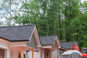 Upon the construction of the new house, asphalt shingles workers covered the roof in construction...