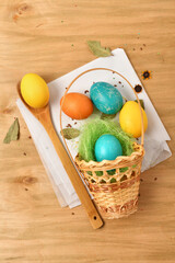easter eggs in a nest of grass in a basket, wooden background, holiday still life and decorations
