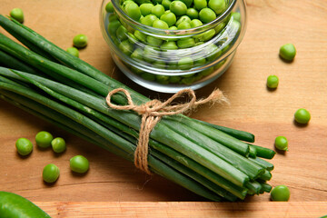 vegetables on a wooden kitchen board, sliced green onions, peas on a wood background, concept of fresh and healthy food, still life